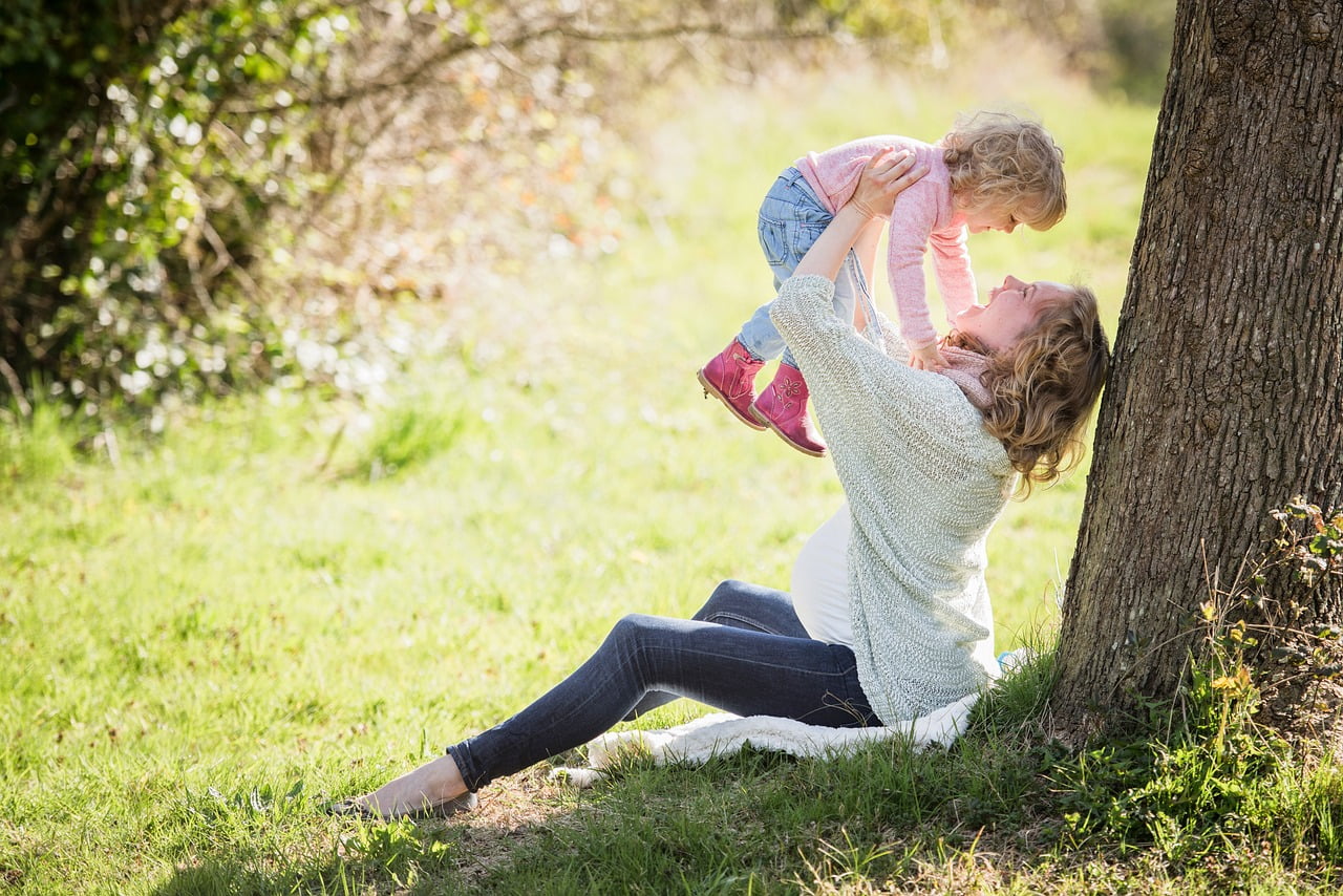 A parent playing with a child in a sunny park — common-law family life