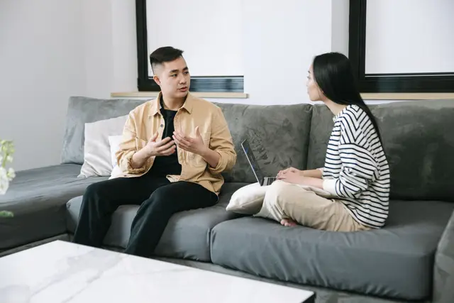 Couple sitting on a couch with a laptop, calmly negotiating their separation agreement at home