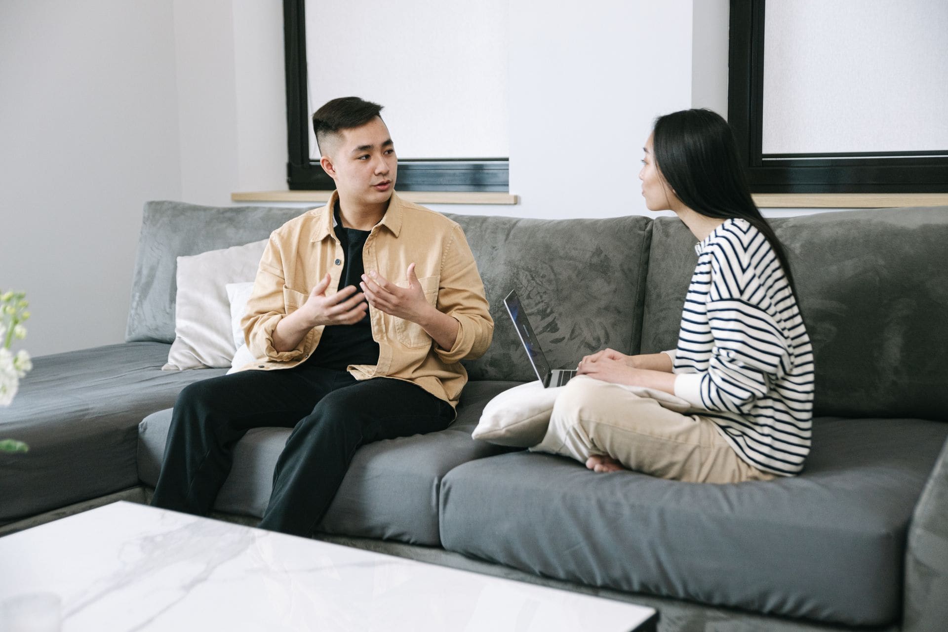 Couple sitting on a couch with a laptop, calmly negotiating their separation agreement at home