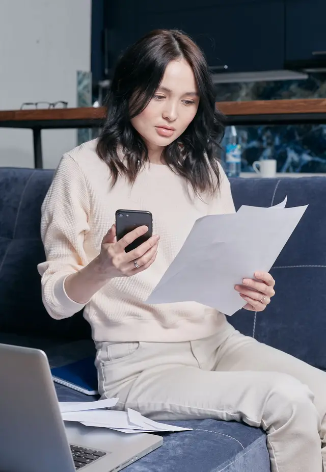 Woman comparing separation and divorce documents on a couch in BC