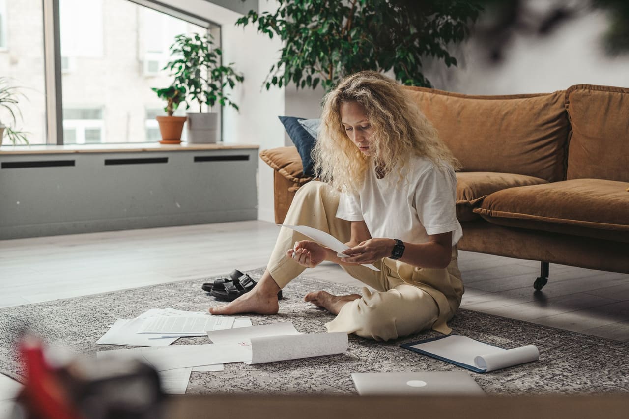 Woman sitting on her living-room floor reviewing separation and divorce paperwork in British Columbia